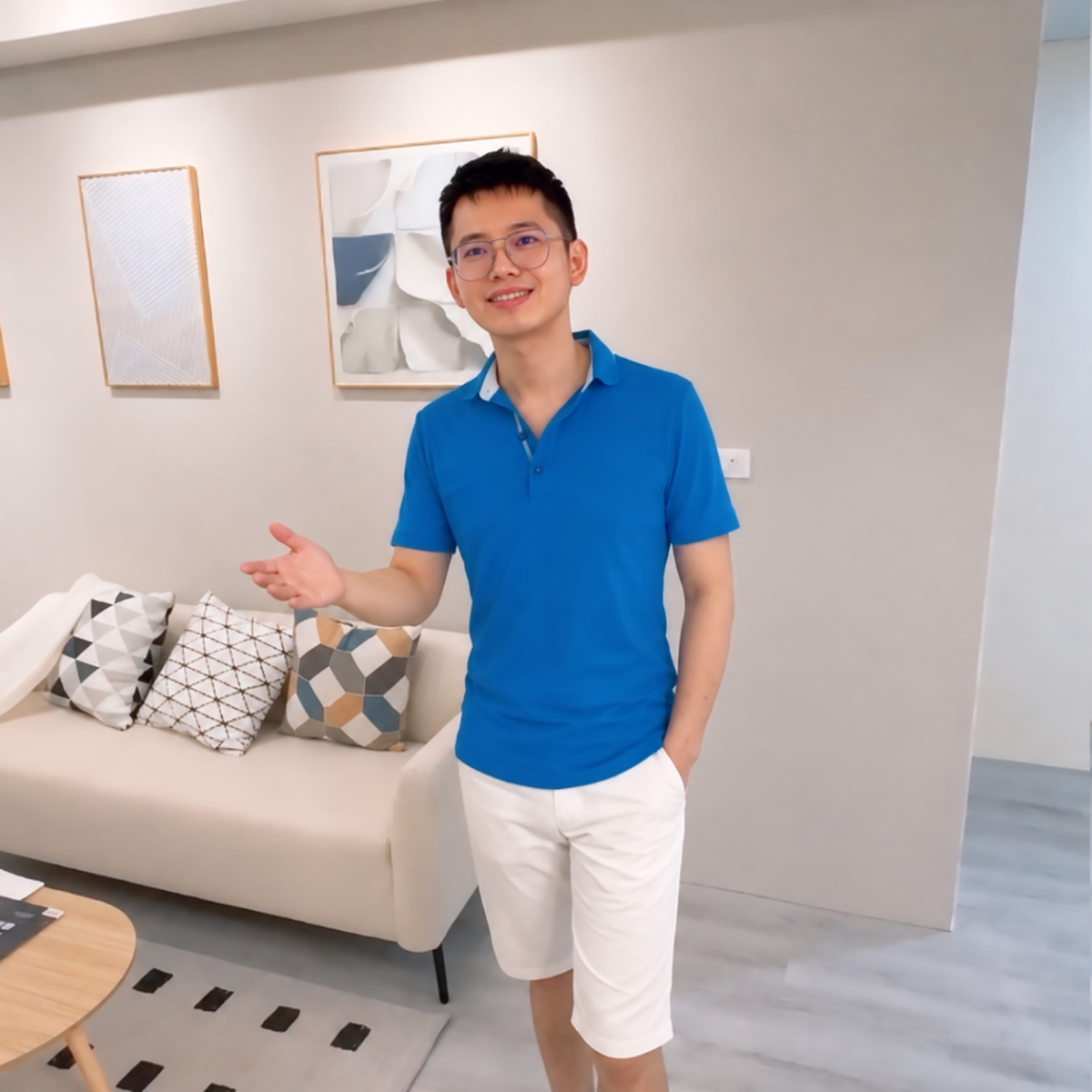 講師忠諺穿著藍色上衣，在明亮客廳中微笑迎賓